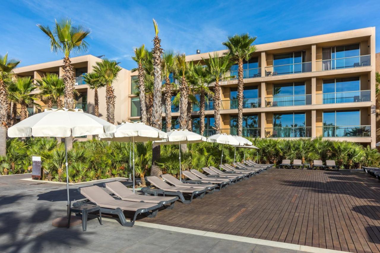 Lago Montargil&Villas Esterno foto The photo shows a modern resort or hotel area featuring several lounge chairs lined up on a wooden deck. Each lounge chair is paired with a white umbrella, providing shade. In the background, there are palm trees, which add to the tropical atmosphere