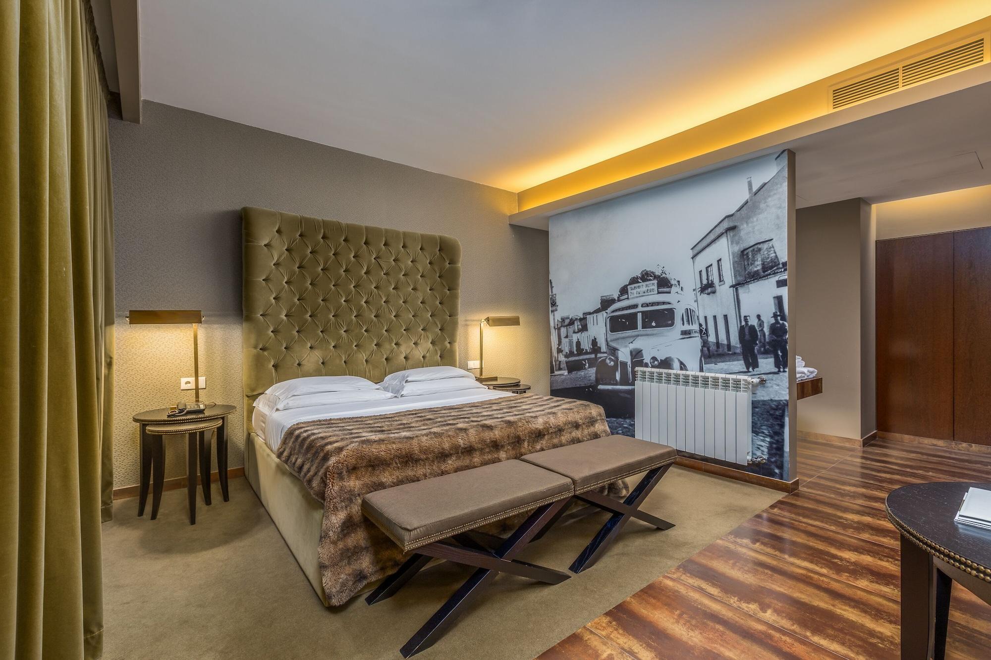 Lago Montargil&Villas Esterno foto The photo shows a modern hotel room featuring a king-sized bed with a tufted headboard, dressed in white linens and a decorative throw blanket. On either side of the bed, there are bedside tables with lamps. The room is well-lit, with an ambient ceil