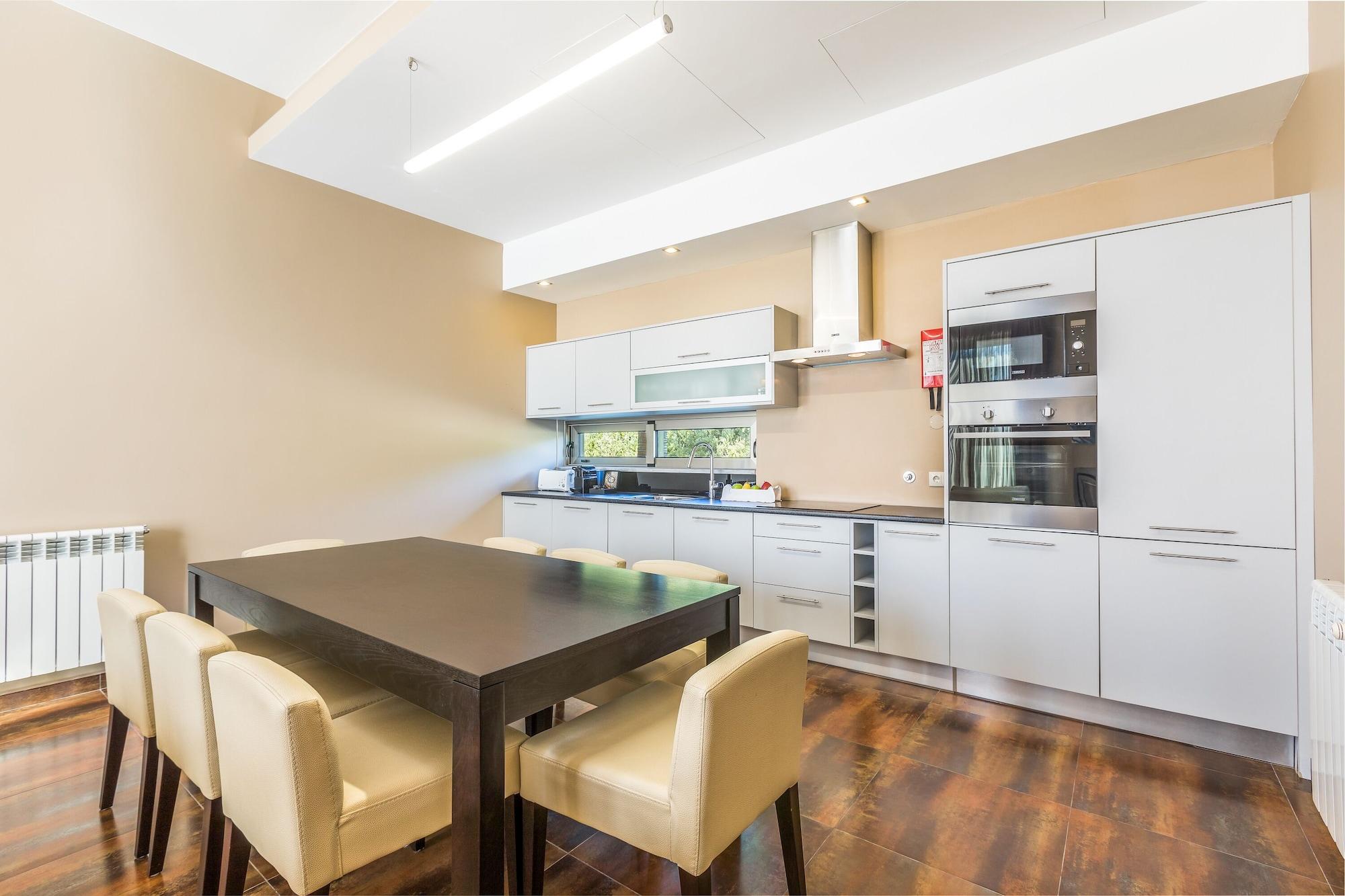 Lago Montargil&Villas Esterno foto The photo shows a modern kitchen with a dining area. The kitchen features sleek, light-colored cabinets and countertops, including built-in appliances. There's a medium-sized dining table with dark wood and four light-colored chairs around it. The wa