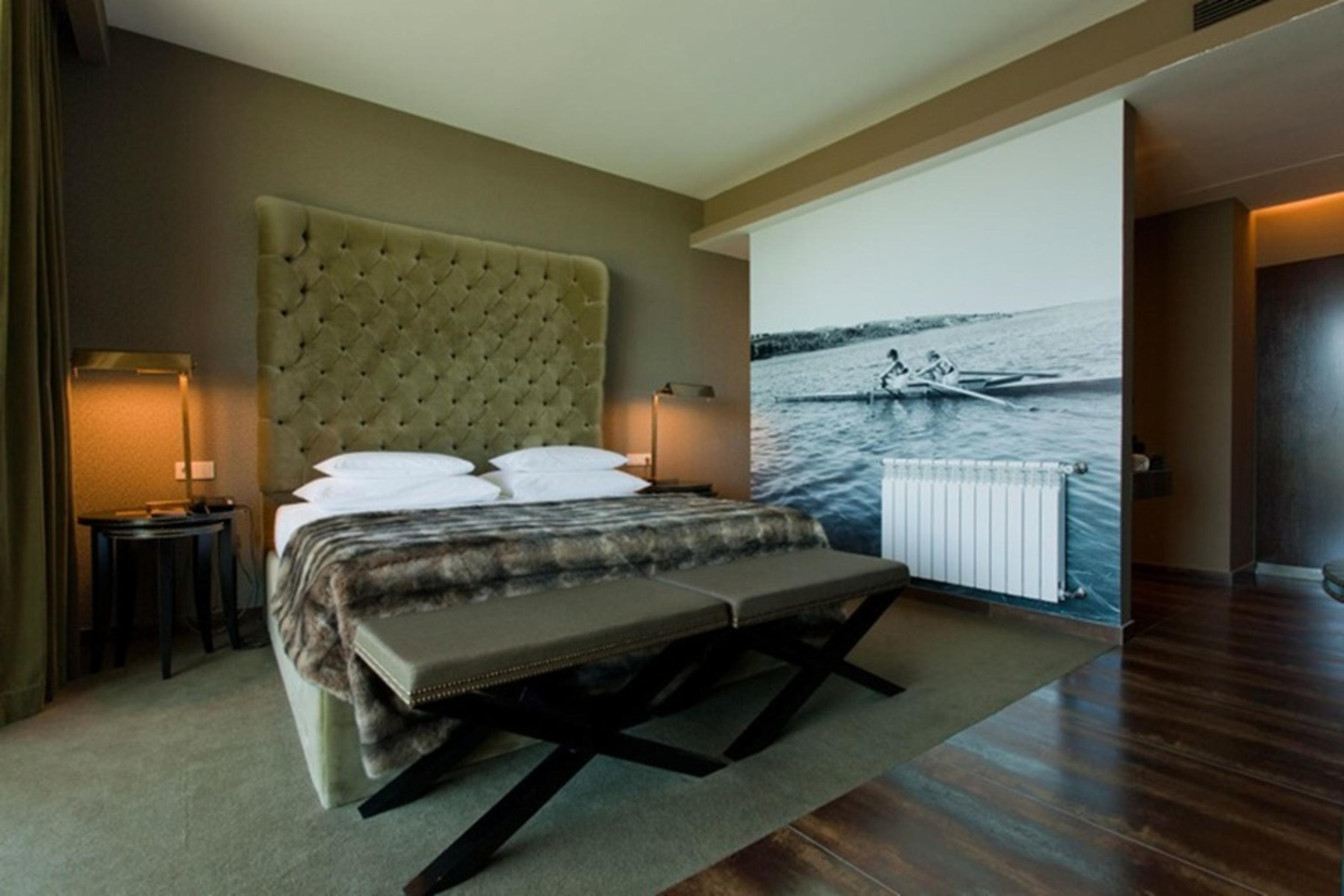 Lago Montargil&Villas Esterno foto The photo shows a modern hotel room featuring a large bed with a tufted headboard and plush bedding. The color palette is neutral, with shades of green and gray. On one side of the room, there are bedside tables with lamps. A comfortable bench sits a