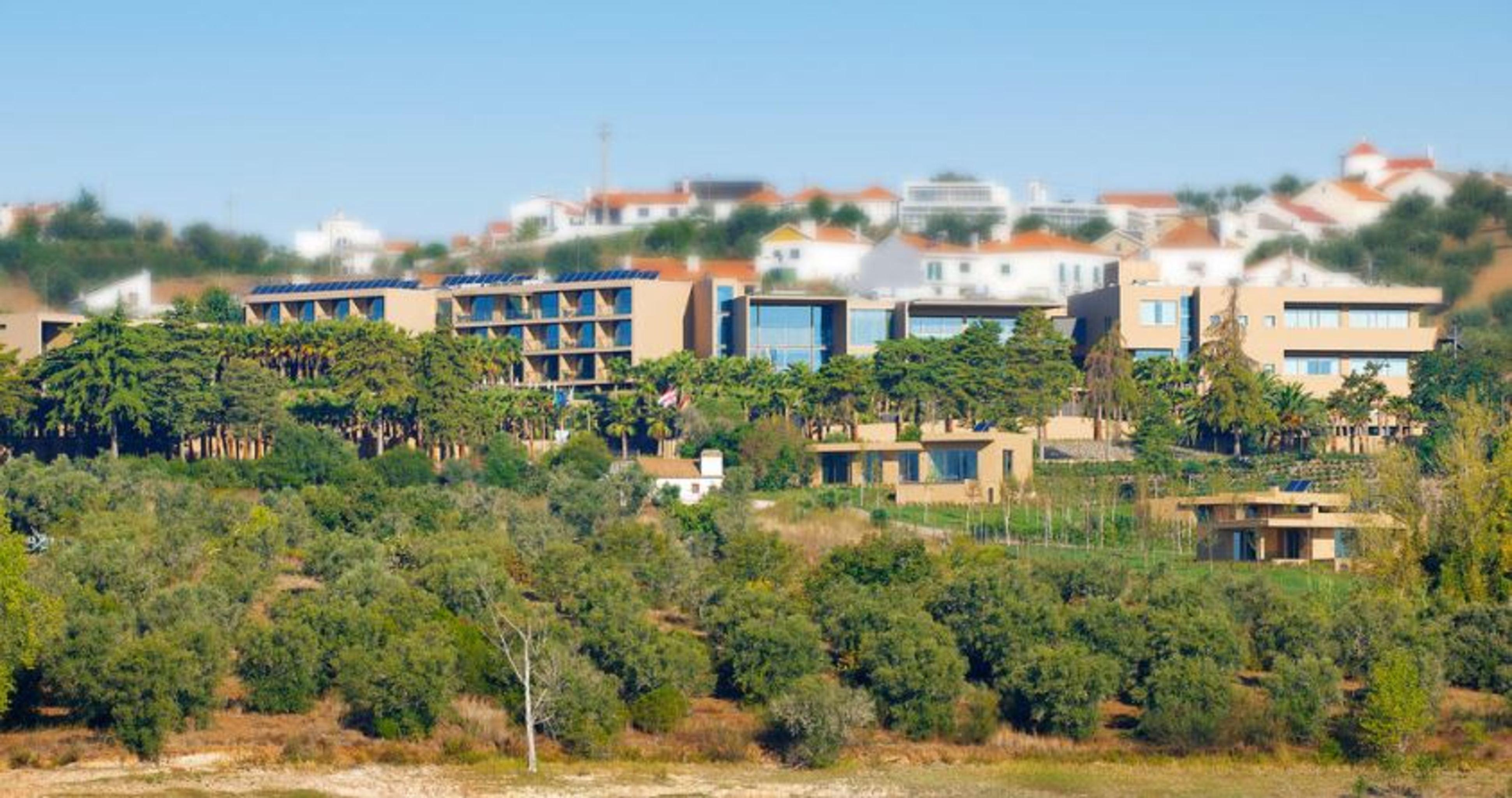 Lago Montargil&Villas Esterno foto The photo shows a hillside view of a modern resort or hotel complex surrounded by greenery. The buildings are designed with a blend of contemporary architecture and natural elements, featuring wooden accents, large windows, and terraces. In the backg