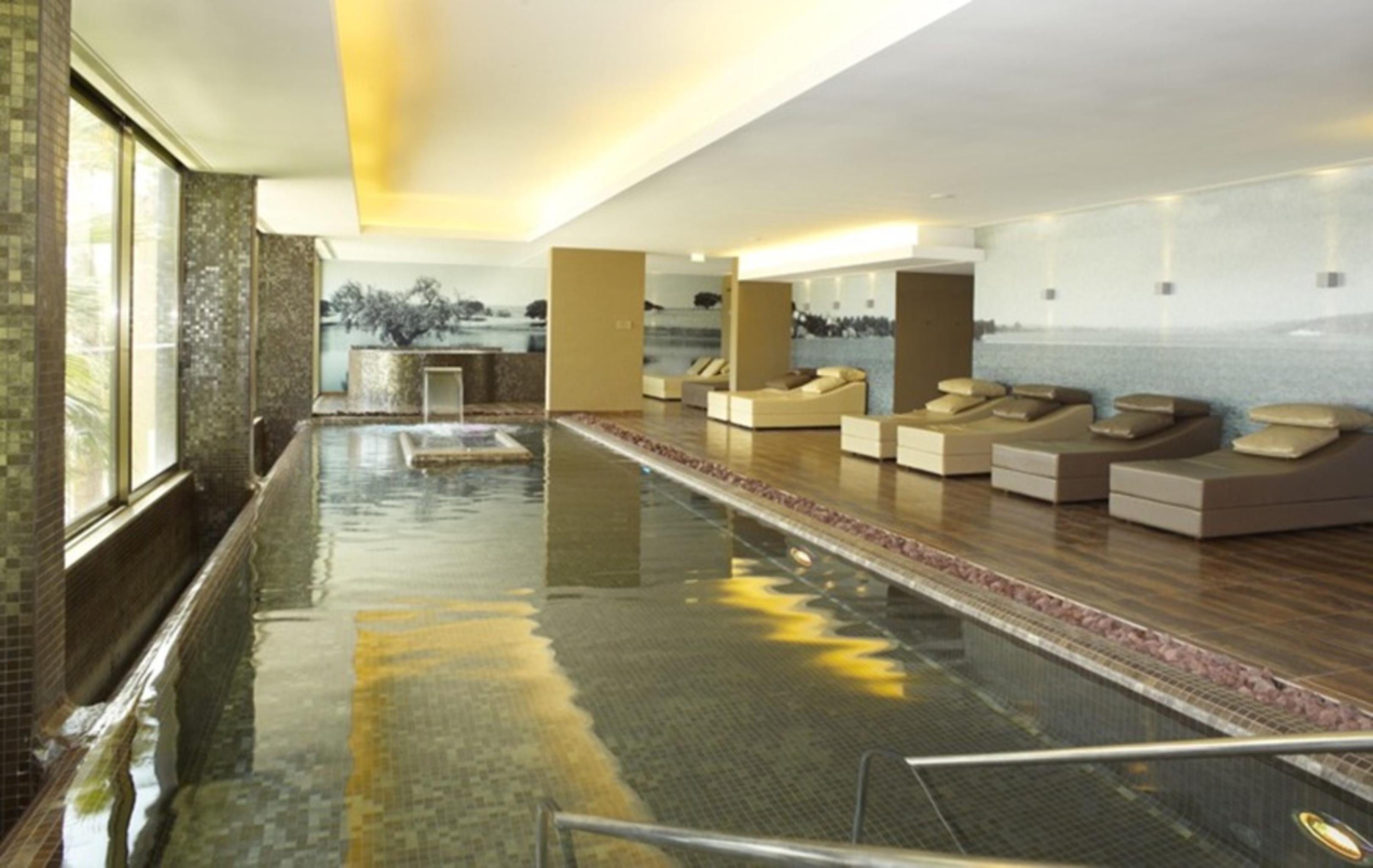 Lago Montargil&Villas Esterno foto The photo shows a modern, serene spa environment. There is a swimming pool with calm water, reflecting the surrounding decor. Along the sides, there are several comfortable lounge chairs arranged, perfect for relaxation. Large windows allow natural l